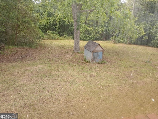 view of yard featuring a storage shed, an outbuilding, and a forest view
