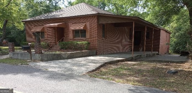view of front of property featuring brick siding, driveway, and an attached carport
