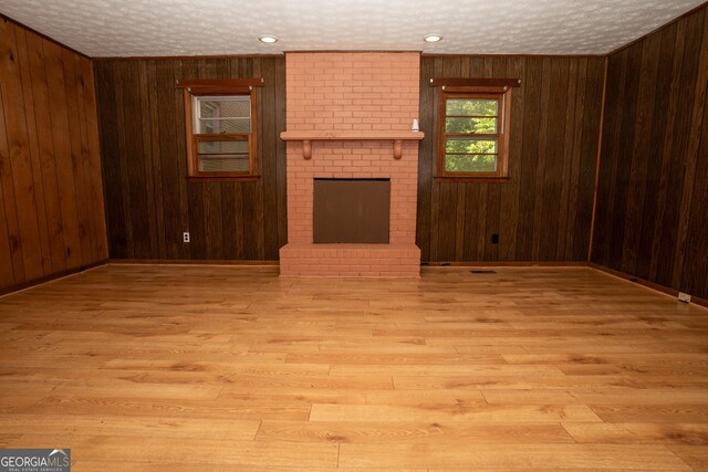 unfurnished living room featuring wood walls, a brick fireplace, and wood finished floors