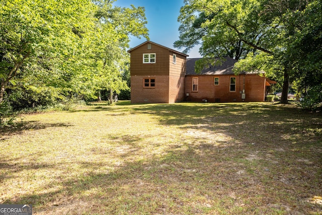 rear view of property featuring a yard and brick siding