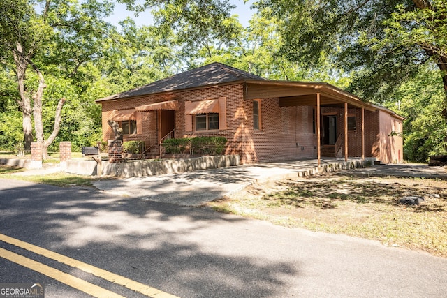 view of front of property with driveway, brick siding, and a carport