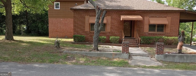 rear view of property with a yard, brick siding, crawl space, and roof with shingles
