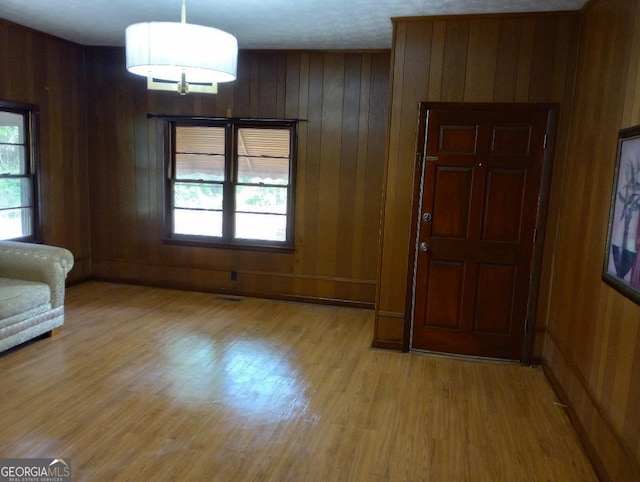 interior space with wooden walls, a healthy amount of sunlight, and light wood-style flooring