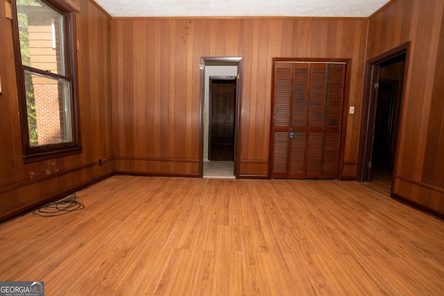 unfurnished bedroom featuring a closet, wood walls, and light wood-type flooring