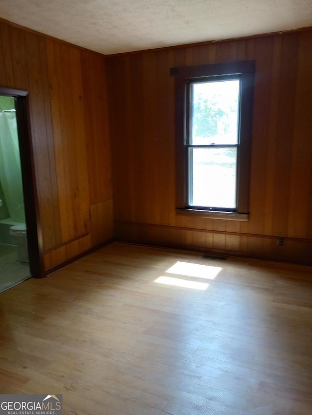 empty room with wooden walls and light wood-type flooring
