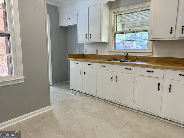 111 Howard St, Byron, GA 31008 - kitchen featuring white cabinets, light tile patterned floors, crown molding, and a sink
