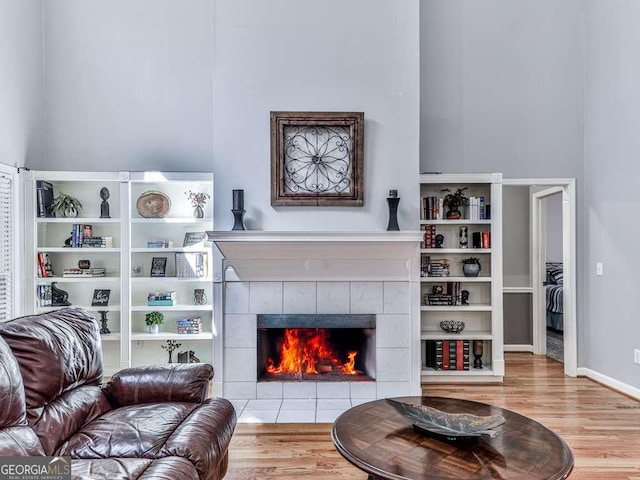living room with baseboards, a tiled fireplace, and wood finished floors