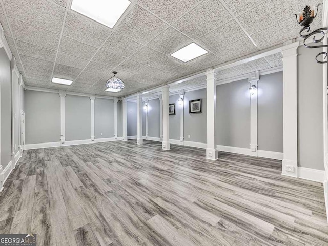 below grade area featuring baseboards, a drop ceiling, and wood finished floors