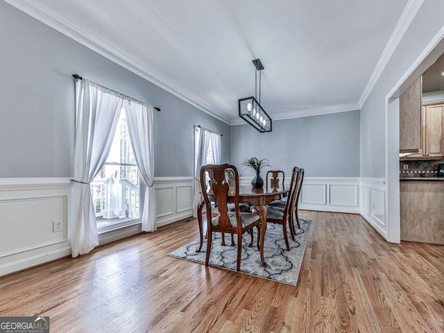 dining space featuring an inviting chandelier, crown molding, and a decorative wall