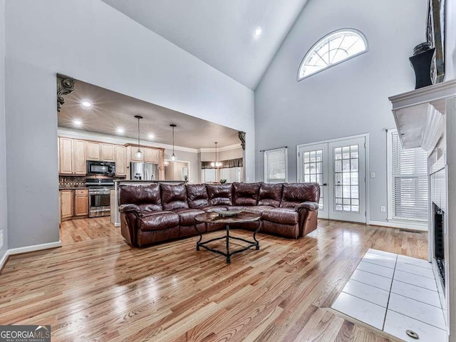 living room featuring high vaulted ceiling, baseboards, and light wood finished floors