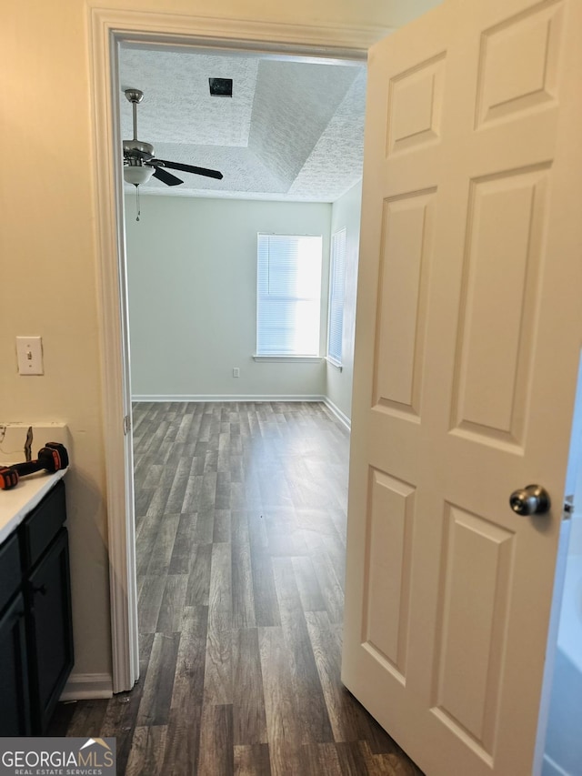 hallway featuring dark wood-style flooring and baseboards
