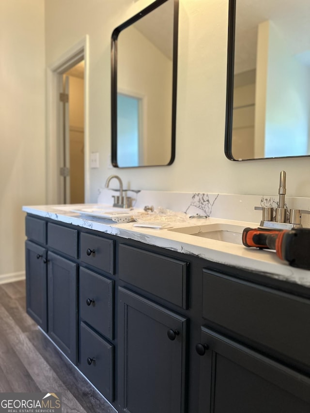 bathroom featuring double vanity, a sink, and wood finished floors