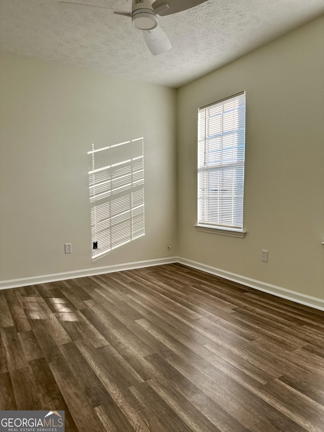empty room with baseboards, a ceiling fan, dark wood finished floors, and a textured ceiling