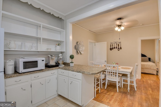 2327 Redwood Dr, Augusta, GA 30904 - kitchen with crown molding, white cabinets, ceiling fan, open shelves, and white microwave