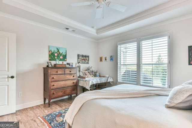 5641 Tisbury Ct, Hoschton, GA 30548 - bedroom with visible vents, crown molding, baseboards, a tray ceiling, and light wood-style flooring