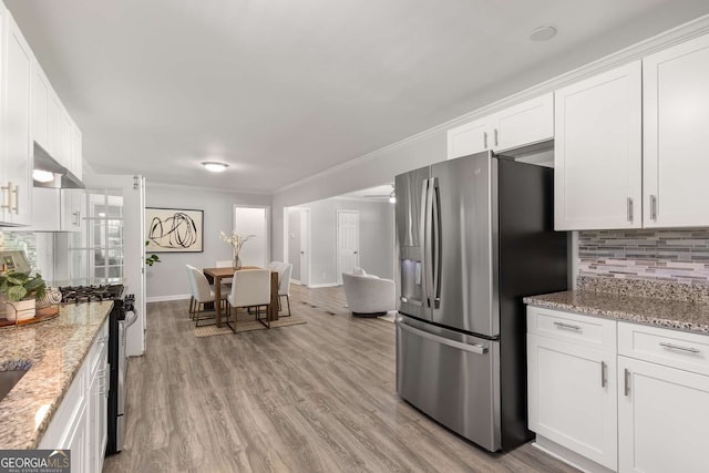 kitchen with backsplash, light stone counters, white cabinets, light wood-style floors, and stainless steel appliances