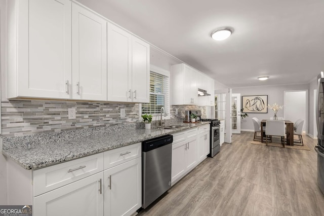 kitchen featuring white cabinets, appliances with stainless steel finishes, a sink, and light wood-style flooring