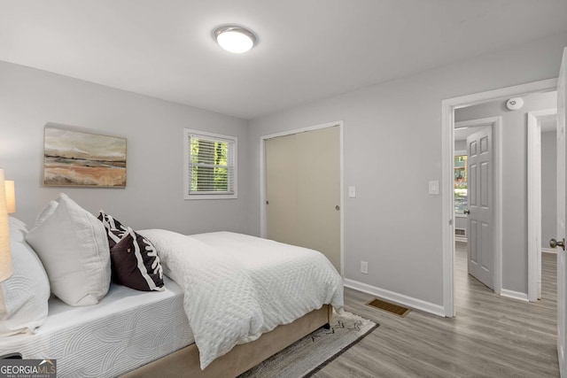 bedroom featuring baseboards, wood finished floors, and visible vents