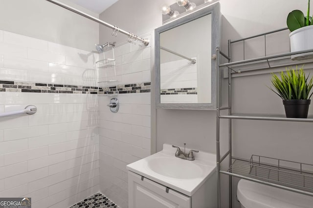bathroom with vanity, toilet, and tiled shower