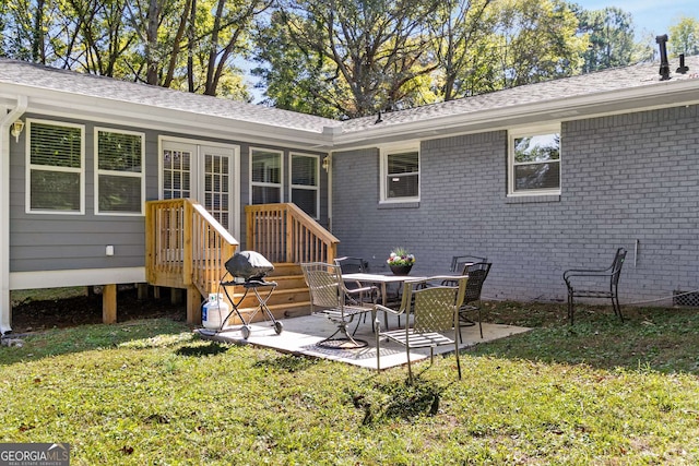 rear view of house featuring a patio, a shingled roof, a lawn, and brick siding