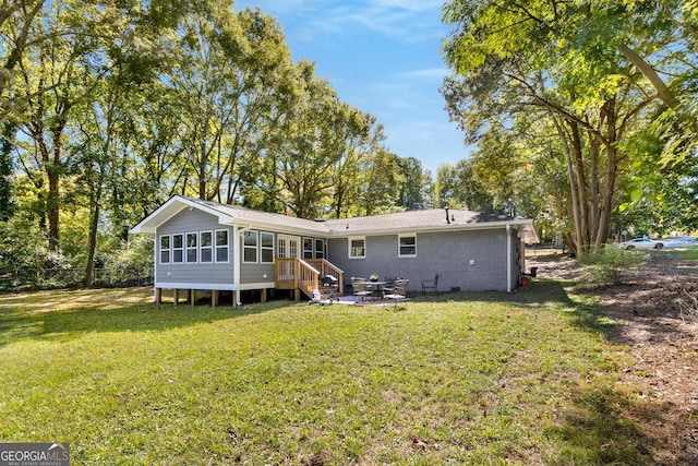 back of property with a sunroom, a patio area, and a lawn