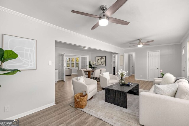 living area featuring baseboards, crown molding, ceiling fan, and wood finished floors