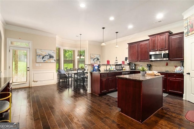 108 Telfair Ln, Mcdonough, GA 30253 - kitchen featuring stainless steel microwave, reddish brown cabinets, a peninsula, dark wood finished floors, and wainscoting