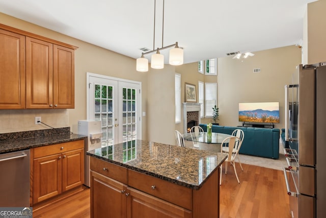 kitchen featuring light wood-type flooring, appliances with stainless steel finishes, open floor plan, and french doors