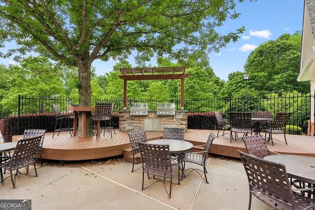 view of patio / terrace with outdoor dining area, exterior kitchen, a wooden deck, fence, and view of scattered trees