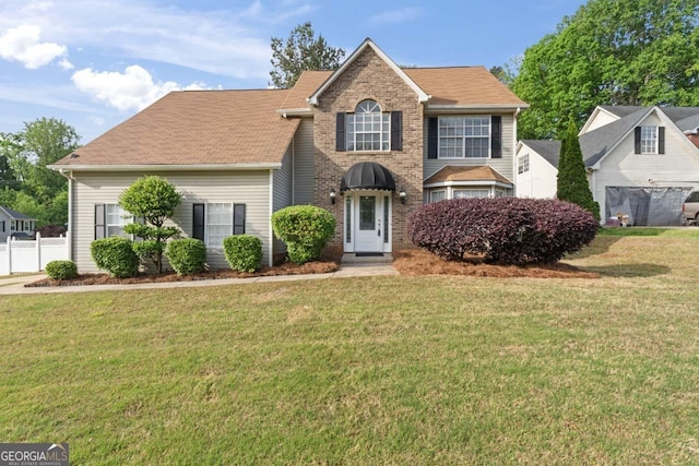 view of front of home featuring brick siding, a front lawn, and fence