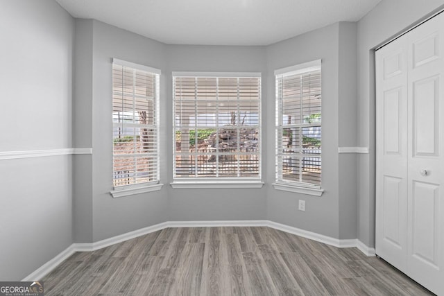 unfurnished bedroom featuring baseboards, wood finished floors, and a closet