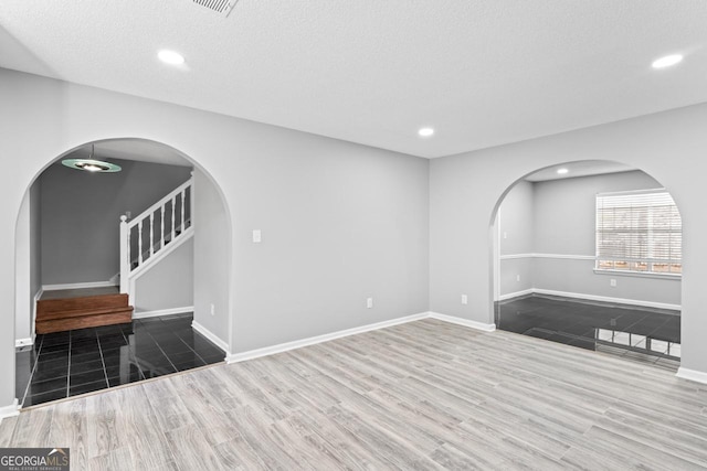 spare room with baseboards, arched walkways, and stairway