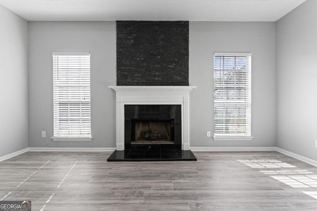 unfurnished living room with baseboards, wood finished floors, and a tile fireplace