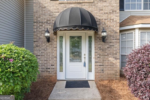view of exterior entry featuring brick siding