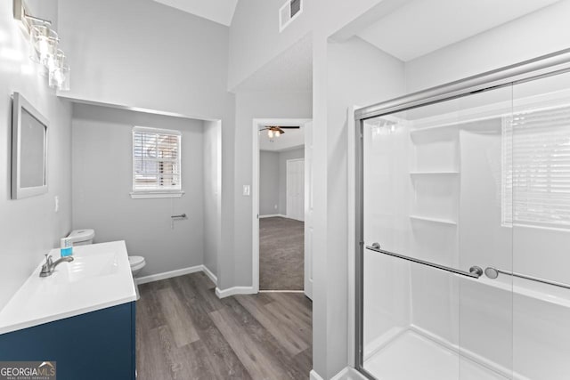 bathroom featuring a stall shower, toilet, wood finished floors, and visible vents