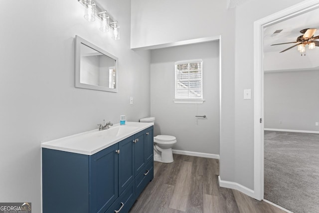 bathroom with vanity, wood finished floors, toilet, baseboards, and a ceiling fan