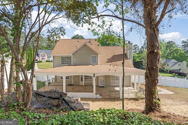 back of house featuring a patio, fence, a chimney, and roof with shingles