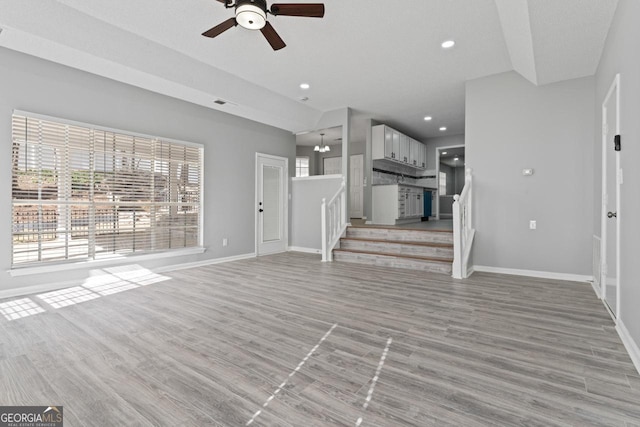 unfurnished living room featuring ceiling fan, stairs, baseboards, recessed lighting, and light wood-style flooring