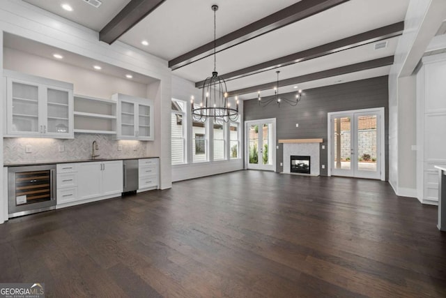 7285 Cordery Rd, Cumming, GA 30040 - unfurnished living room with bar, beam ceiling, a chandelier, wine cooler, and dark wood-type flooring