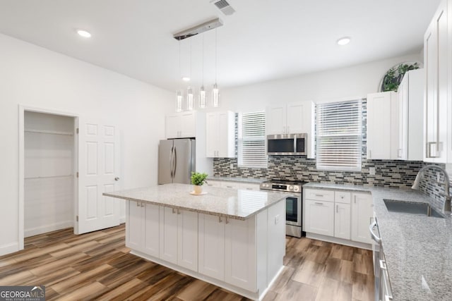 830 Dixon Dr, Gainesville, GA 30501 - kitchen with a sink, stainless steel appliances, decorative backsplash, wood finished floors, and visible vents