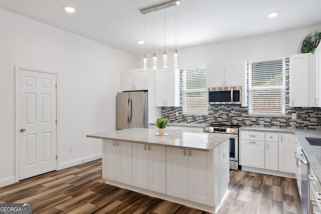 830 Dixon Dr, Gainesville, GA 30501 - kitchen with decorative backsplash, a kitchen island, appliances with stainless steel finishes, dark wood finished floors, and white cabinetry