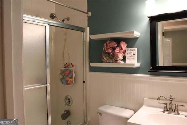 full bathroom with toilet, enclosed tub / shower combo, wainscoting, and vanity