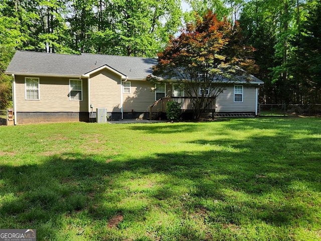 rear view of property featuring a lawn, fence, and a deck