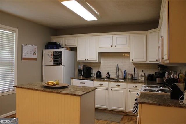 kitchen featuring a center island, tasteful backsplash, a sink, white appliances, and light wood-style flooring