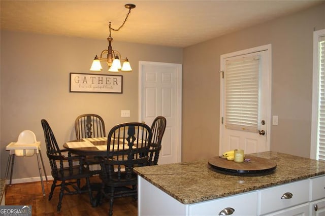 dining space featuring an inviting chandelier, baseboards, and dark wood-style flooring