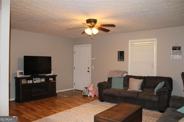 living area featuring a ceiling fan, baseboards, wood finished floors, and a textured ceiling