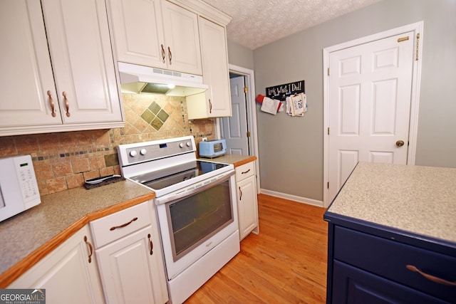 kitchen featuring white appliances, white cabinetry, and under cabinet range hood
