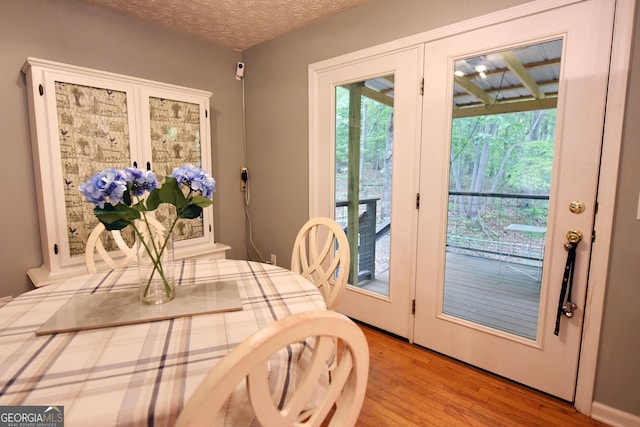 dining space featuring french doors, a textured ceiling, and wood finished floors