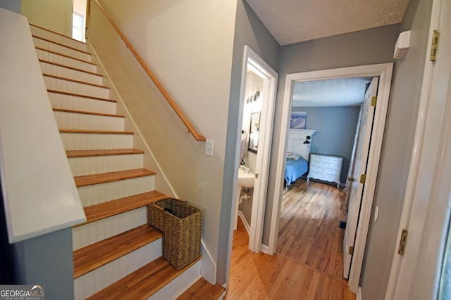 stairs featuring baseboards, a textured ceiling, and wood finished floors