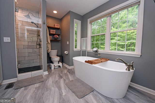 full bathroom with a freestanding bath, toilet, baseboards, a shower stall, and visible vents